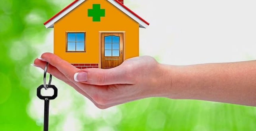 The house with key in the hand on green background